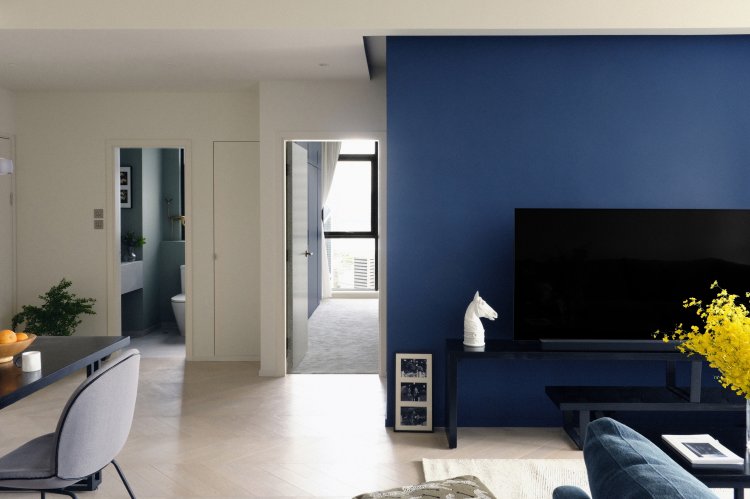 Wohnzimmer mit blauer Wand und hellem Parkett.