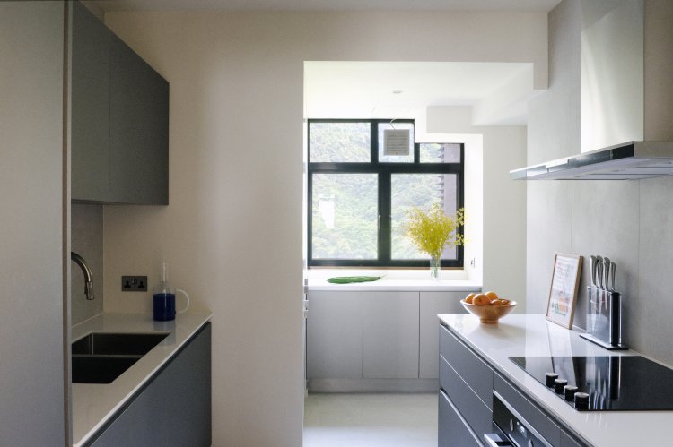 Küche mit Fenster und grauen Küchenschränken.