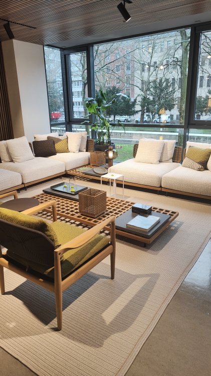 Ein Foto einer Lounge, die aus einem weissen Sofa, einem grünen Sessel und einem Beistelltisch besteht.