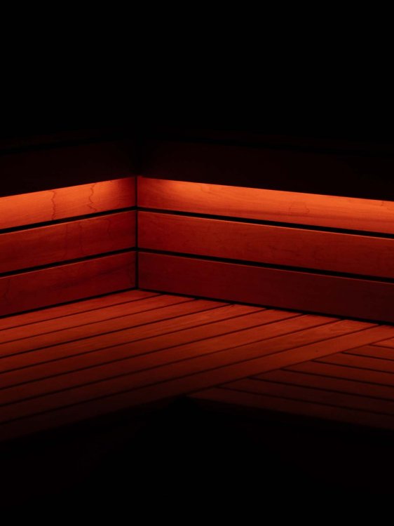 Dunkler Raum mit roten Lichtleisten entlang der Holzbänke, die eine ruhige und zugleich intensive Atmosphäre erzeugen.