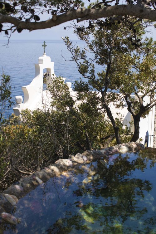 Kapelle von Li Galli mit Meerblick, eingebettet in Natur und Architektur.