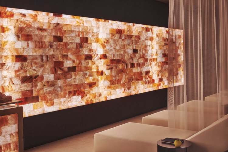 Ruheraum im Schloss Zermatt Spa mit hinterleuchteter Himalaya-Salzwand und Liegen.