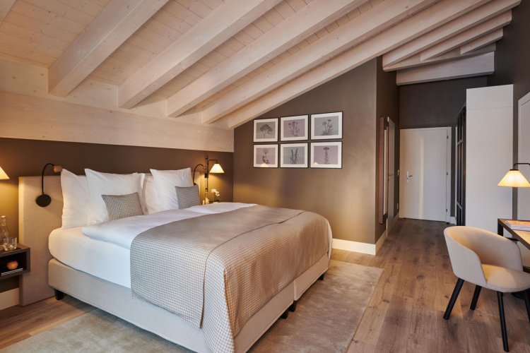 Modernes Doppelzimmer im Schloss Zermatt mit Holzbalkendecke und alpinem Design.