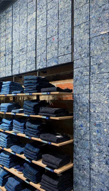 Bekleidungsgeschäft mit Wandverkleidung aus blauen FabBRICK-Ziegeln hinter Jeansregalen.