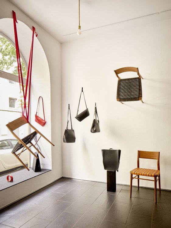 Minimalistisch gestalteter Ladenraum mit hängenden Ledertaschen und ausgewählten Möbelstücken.