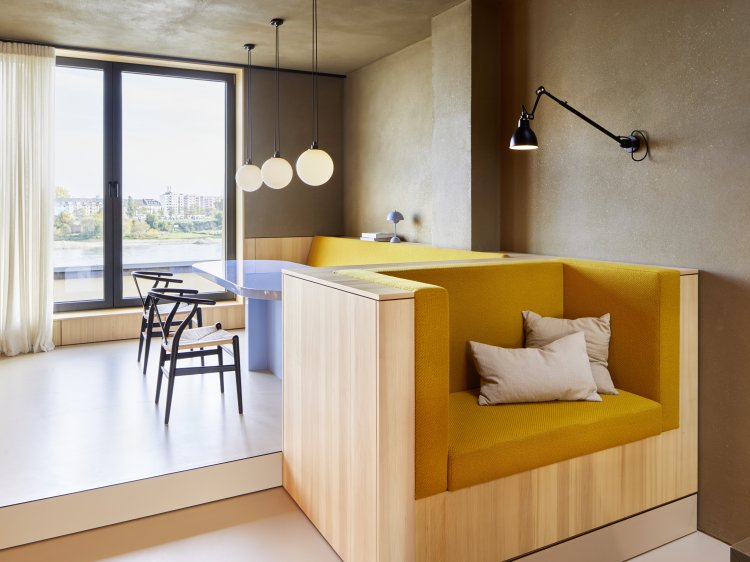 Wohnzimmer mit einem Sofa aus Holz, hinten ein Tisch mit Stühlen