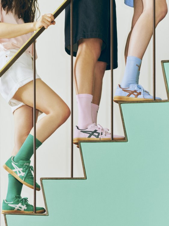 Drei Personen mit kurzen Hosen und Sneakers an den Füssen stehen auf einer Treppe