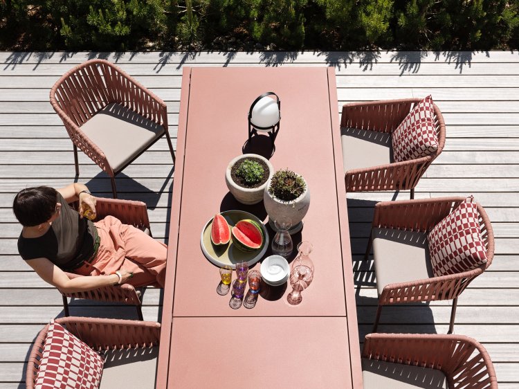 Eine Frau sitzt an einem rosa Tisch in einem Garten