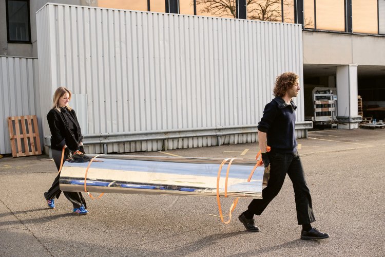 eine Frau und ein Mann tragen gemeinsam ein Metallteil