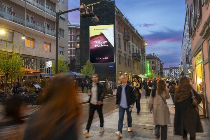 Menschen in der Dämmerung auf dem Corso Garibaldi. An einer Hauswand im Hintergrund das Messeplakat.