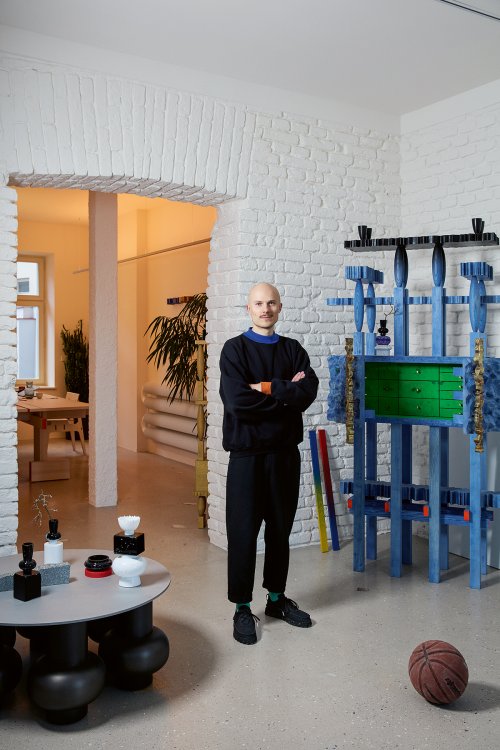 Mann steht in einem Zimmer vor einem blauen Regal.