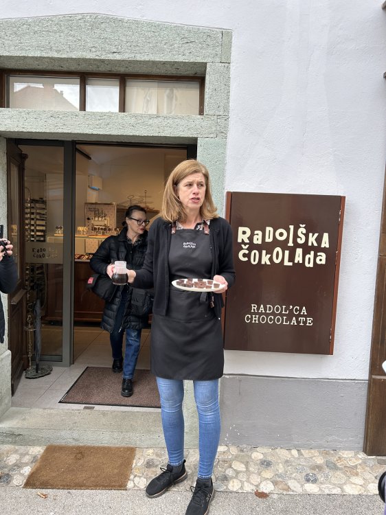 Eine Frau steht mit einem Tablett voller Schokolade vor einem Laden.