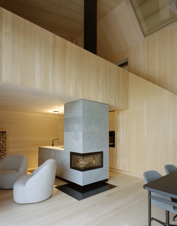 Das Innere des Tiny House ist komplett aus hellem Tannenholz gestaltet. Der offene Wohnbereich erstreckt sich über zwei Stockwerke, ein Ofen aus Muschelkalk ist das Verbindungselement und Bestandteil der Küche.