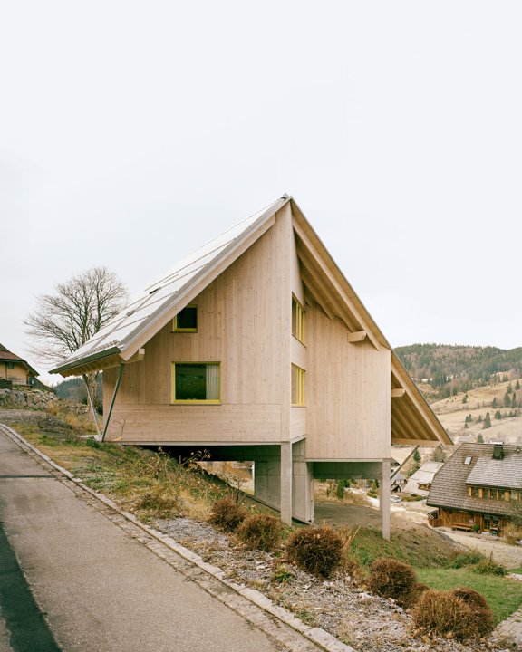Blick auf ein Haus aus Holz steht an einem Hügel.