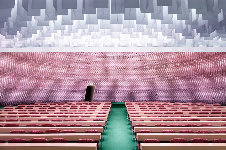 Eine Fotografie des Künstlers Luca Zanier zeigt einen leeren Saal in rot- und rosafarbenen Tönen.