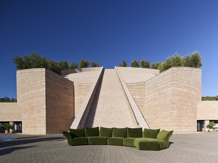 Das intensive Grün Material" des Sofas erinnert mit dem Materials "Every Place" an die Weinreben, die das Weingut umgeben. Im Hintergrund der spektakuläre, zylinderförmige Baukörper mit der Freitreppe.
