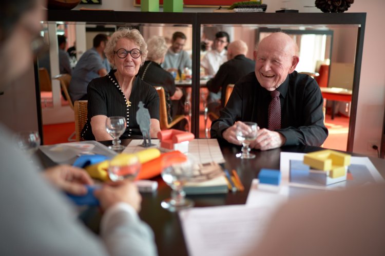 Trix und Robert Haussmann sitzen in ihren eigenen vier Wänden am Tisch, der mit Ideenskizzen und Modellen der Lehrstücke Hommage à Gerrit Rietveld belegt ist.