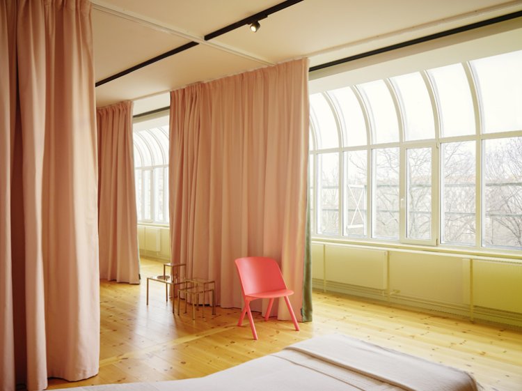Verschiedene farbige Trennvorhänge zonieren einen luftartigen Raum mit langer Fensterfront.