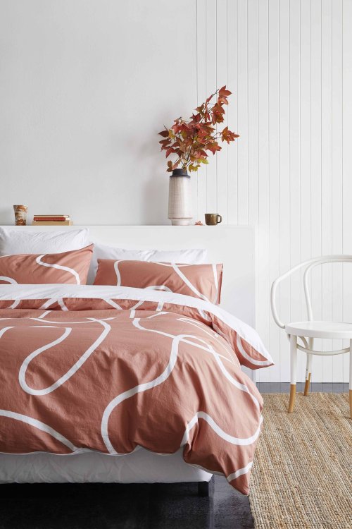 Das neue Bettwäsche-Set von Undercover Living in Terrakotta mit weissem Linien-Muster, dahinter ein herbstlicher Blumenstrauss.