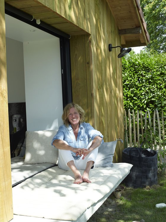 Die Innenarchitektin Dominique Cha sitzt auf dem Fenster-Fouton in ihrer umgebauten Cabin und lacht in die Kamera.