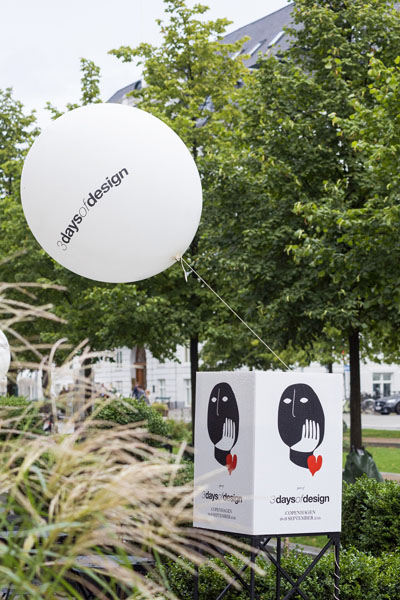 Ein Plakat und ein weisser Ballon mit dem Schriftzug und Logo der 3 days of design sind vor einer grünen Allee fotografiert.