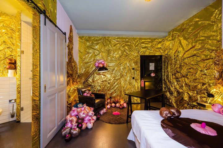 Ein mit goldiger Folie ausgekleidetes Hotelzimmer im Hotel Helvetia in Zürich mit pinken, abstrakten Stoffkugeln und Figuren der Künstlerin Myriam Gämperli anlässlich des Pop-Up Projekts "Hotel Noel".