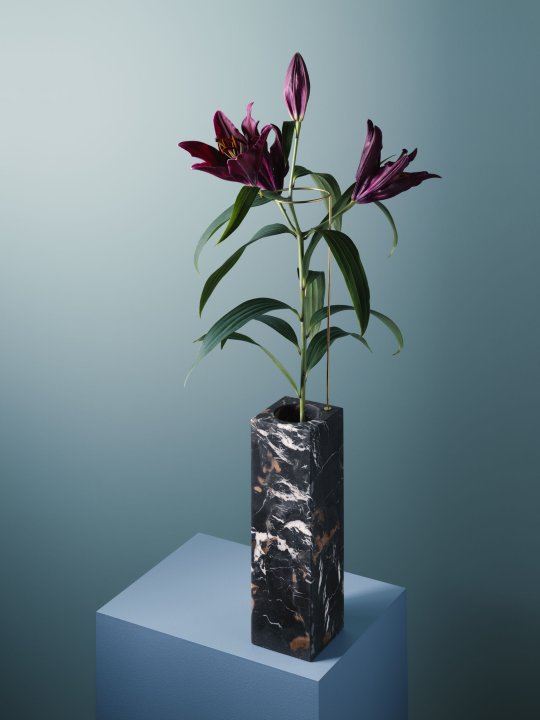 Hohe, rechteckige Trichtervase aus schwarzem Marmor mit einer dunkelvioletten Lilie steht auf einem hellblauen Sockel vor einem türkisblauen Hintergrund von Studio Bloc und Carl Kleiner.