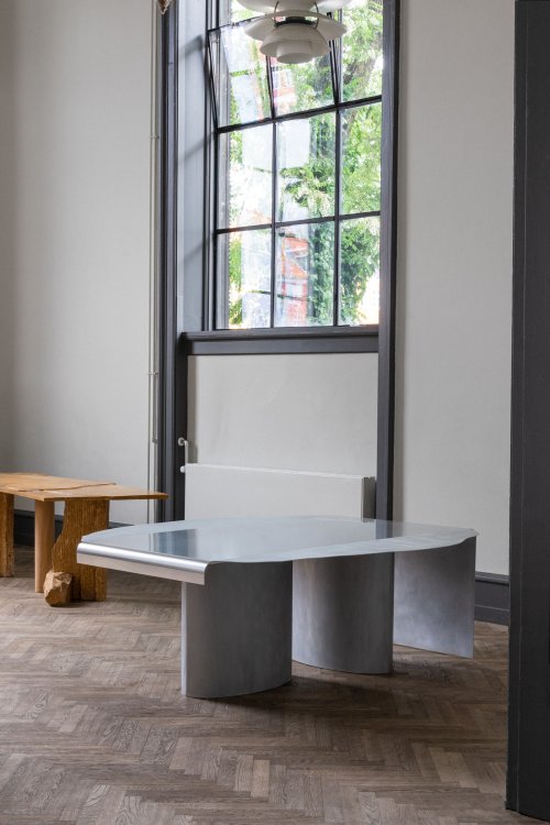 Ein kunstvoller Tischentwurf des Kopenhagener Büros All The Way To Paris mit einem Tischtuch aus Aluminium steht in einem Ausstellungsraum.