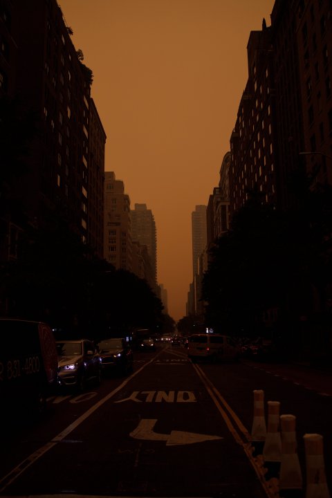 Aufnahme einer Strasse in New York mit Wolkenkratzern links und rechts bei orange-rotem Himmel.