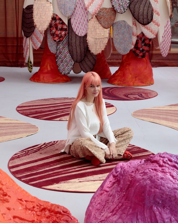 Nadja Stäubli sitzt auf einem von ihr entworfenen Teppich mit abstraktem Muster umgeben von ihrer Installation «Chroma».