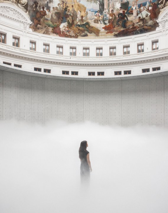 In der runden Halle der Bourse de Commerce liegt dichter weisser Nebel am Boden und eine einzelne Person steht darin, halb verschwunden.