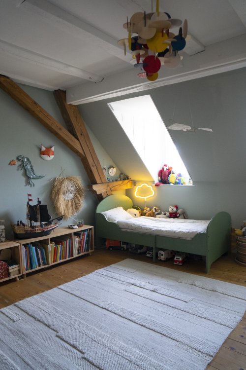 Ein Kinderbett, das unter einem Dachfenster steht.