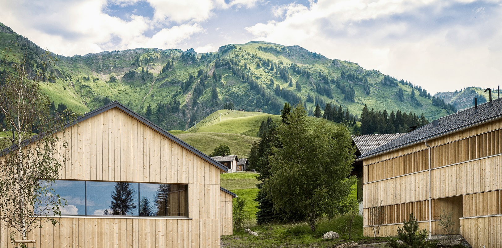 Fuchsegg Eco Lodge Holzgebäude vor grüner Natur mit Bergen im Hintergrund