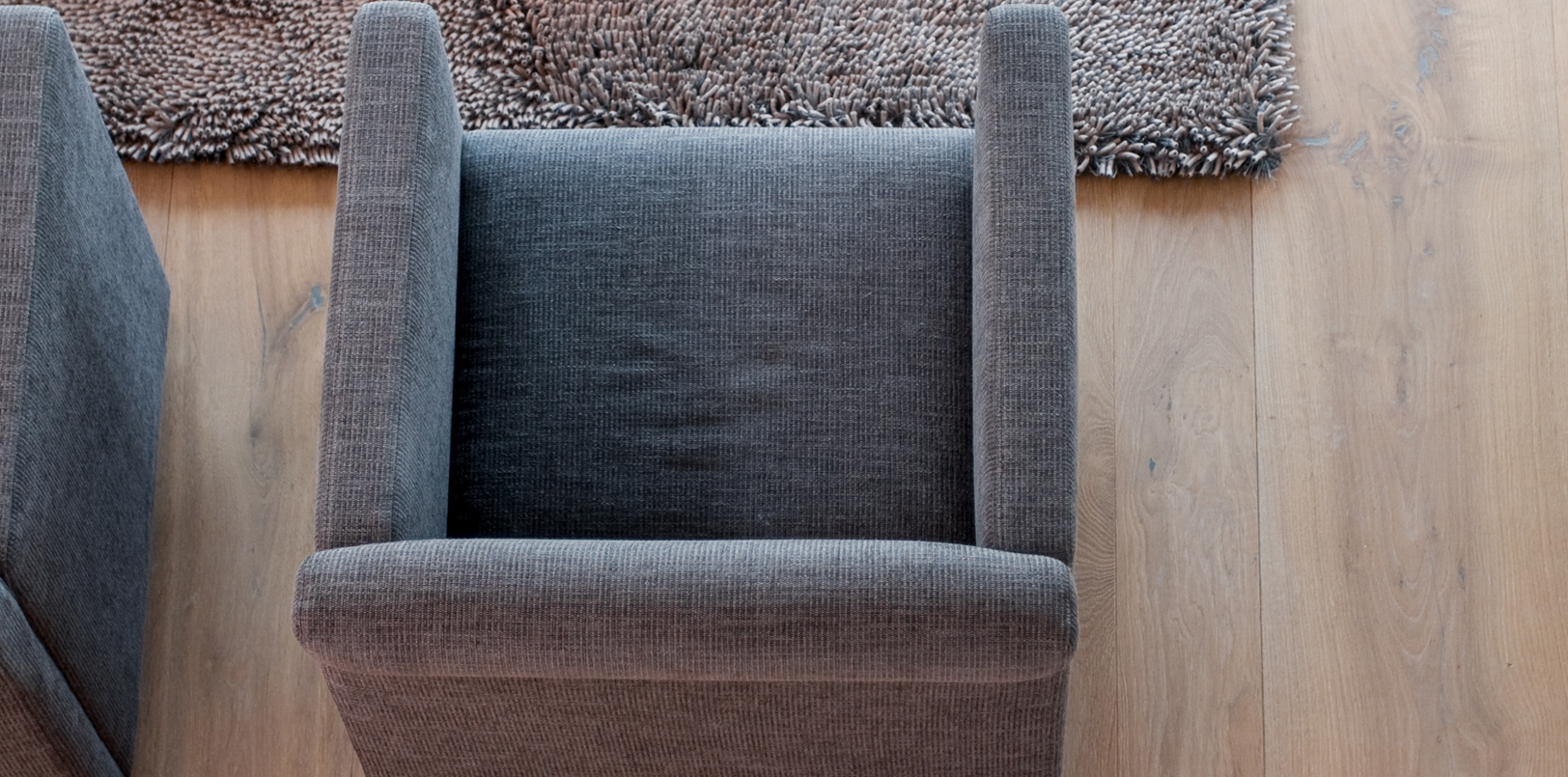 Graues eckiges Sofa und flauschiger Teppich auf Holzboden